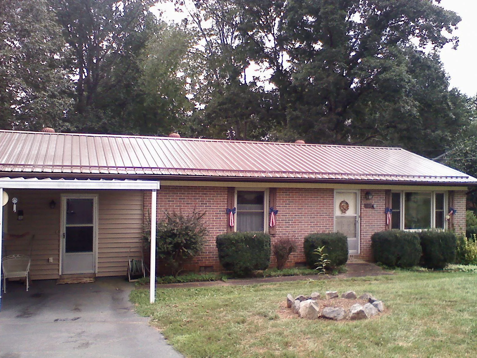 Bronze metal roof and carport on a brick ranch home — Roof Repair work by our crew in Jonesville